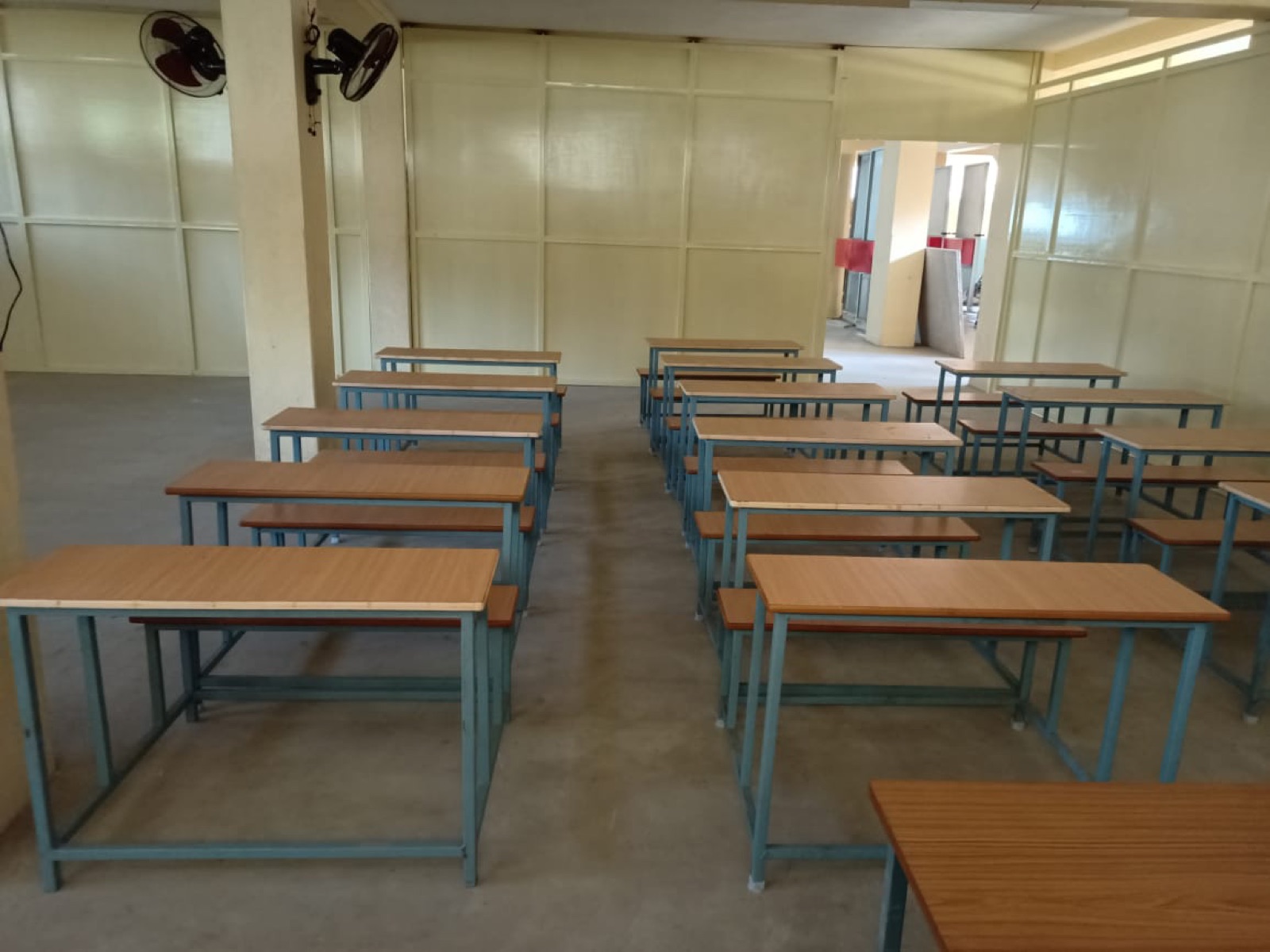 Aula scolastica con file di banchi in legno appena installati